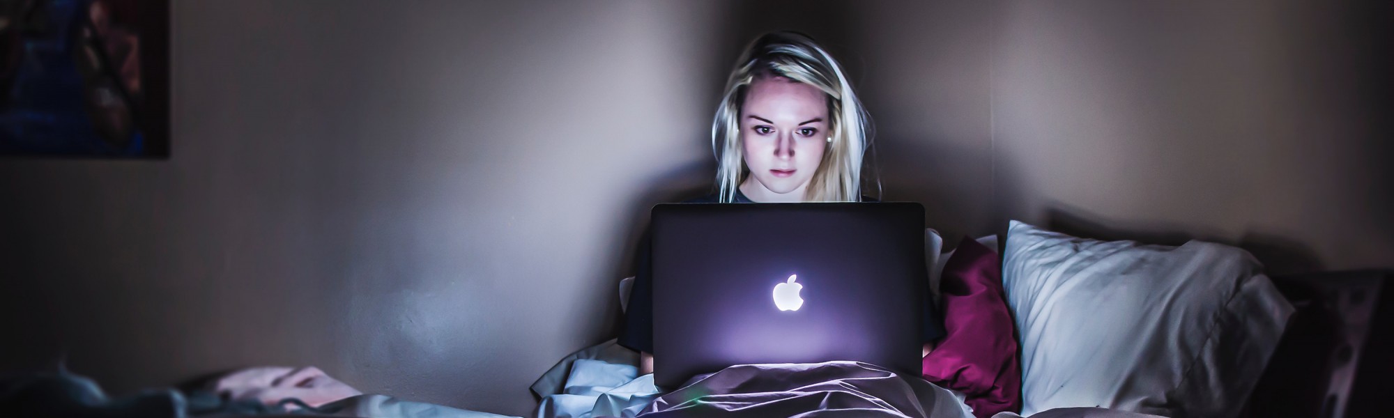 Worried girl looks at her computer in bed.