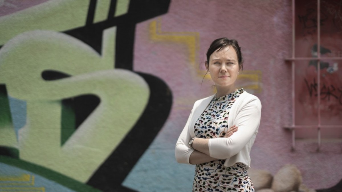 Dr Anna Olsen in front of graffiti wall.