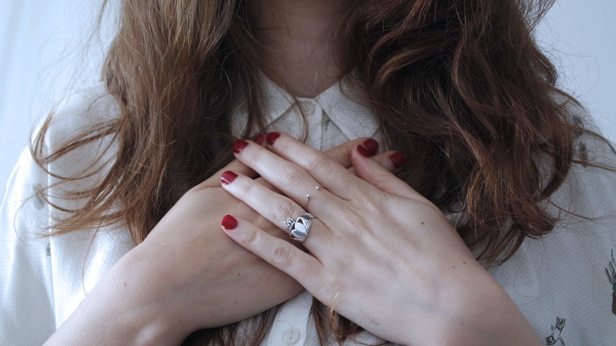 Woman with hands crossed over chest, a sign of self-compassion