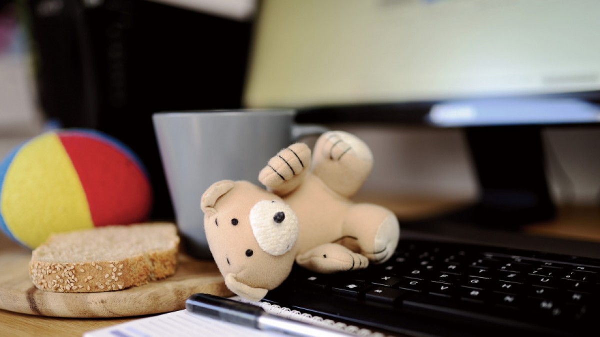 Teddy bear, a slice of bread and ball next to keyboard.