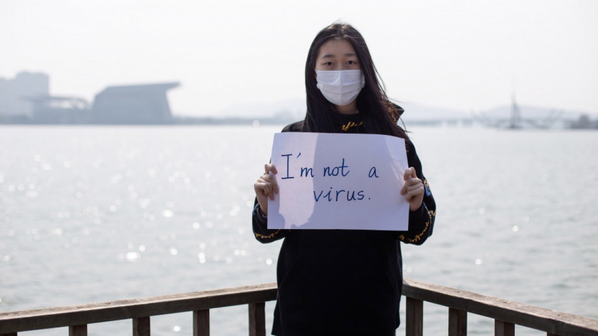 Girl with mask holds a sign saying &#039;I am not a virus&#039;.